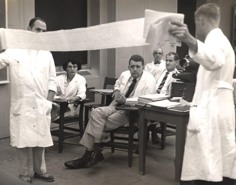 Dr. Eugene Braunwald (seated front left) and Dr. Nina Starr Braunwald (seated right) study an electrocardiogram printout, circa 1963. (Photo courtesy of the Office of NIH History and Stetten Museum)